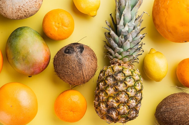 Conjunto de frutas tropicales, sobre fondo amarillo con textura de verano, vista superior plana