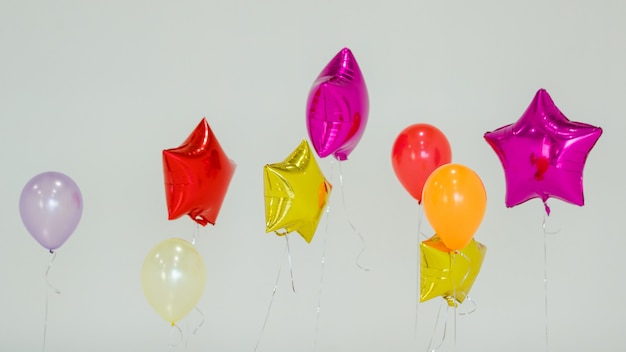 Conjunto de globos de helio multicolores de varios colores flotando sobre fondo gris durante la celebración navideña