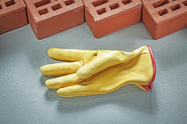 Conjunto de guantes de seguridad de ladrillos de construcción rojos sobre el concepto de construcción de fondo de hormigón.