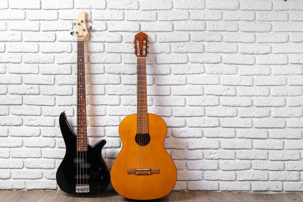 Conjunto de guitarras en el suelo contra la pared de ladrillo blanco.