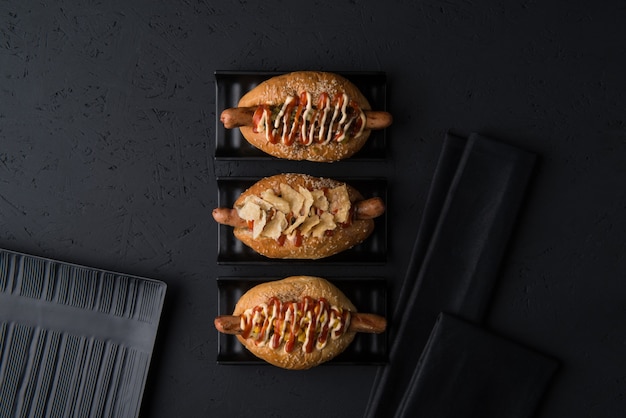 Conjunto de hamburguesas en platos planos sobre fondo negro, vista superior