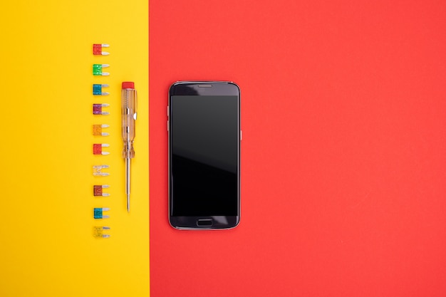 Conjunto de herramienta eléctrica con smartphone negro sobre fondo colorido
