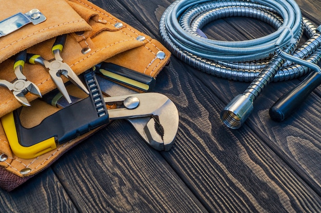 Conjunto de herramientas en la bolsa para fontaneros sobre tablas de madera vintage oscuras