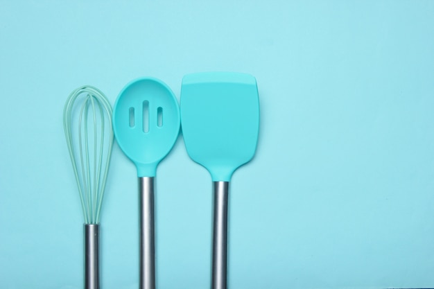 Conjunto de herramientas para cocinar en el azul. Paletas de silicona con asas de metal y batidor. Vista superior. Copia espacio