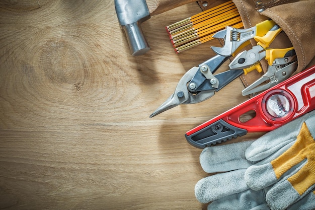 Conjunto de herramientas de construcción en cinturón de herramientas de cuero sobre tablero de madera