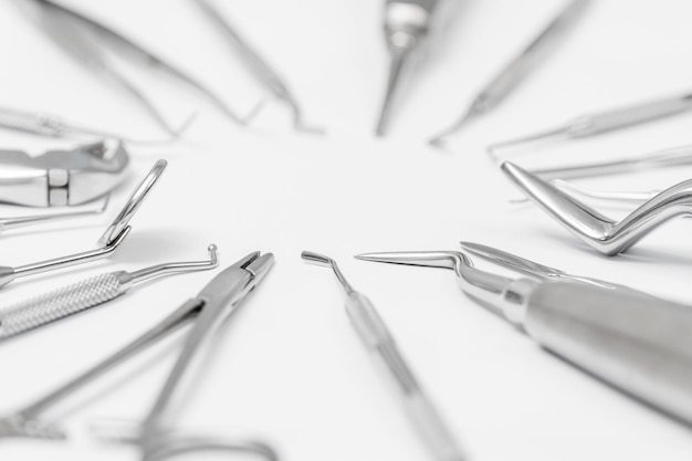 Foto conjunto de herramientas dentales dispuestas en círculo sobre un fondo blanco, borrosas