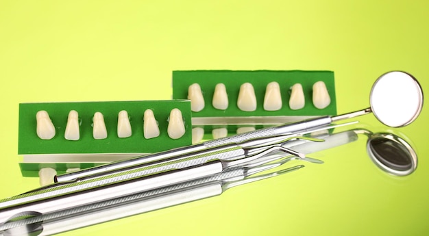 Foto conjunto de herramientas dentales con prótesis sobre fondo verde