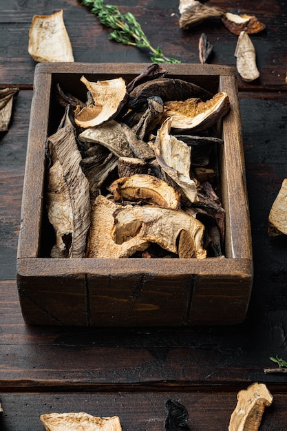 Conjunto de hongos porcini secos, sobre fondo antiguo de mesa de madera oscura.