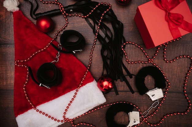 Un conjunto de juguetes para adultos con decoración navideña. Flatley. Un ejemplo de regalo. Esposas, látigo, plug anal, bolas navideñas.