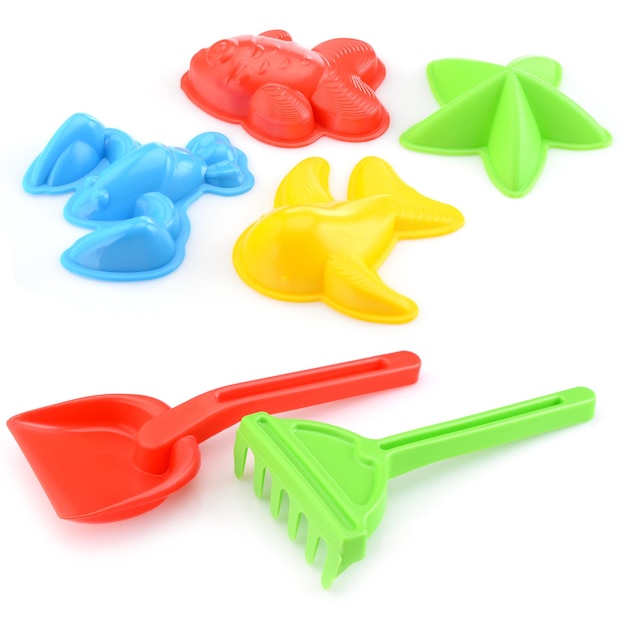 Un conjunto de juguetes para niños para jugar en la caja de arena Rastrillo de colores y una pala de plástico aislado en un primer plano de fondo blanco Concepto de ocio infantil de desarrollo infantil temprano