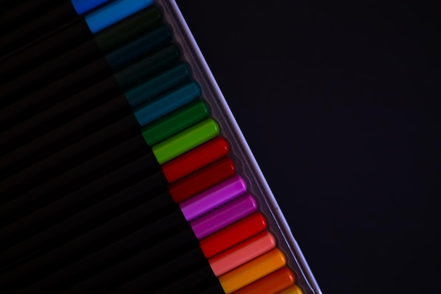 Conjunto de lápices de colores en fondo negro vista superior conjunto de lápizes de colores dispuestos uniformemente en un