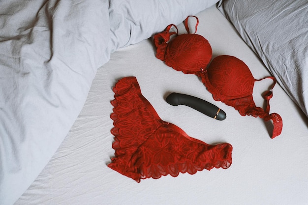 Foto conjunto de lencería roja y consolador vibrador en la cama