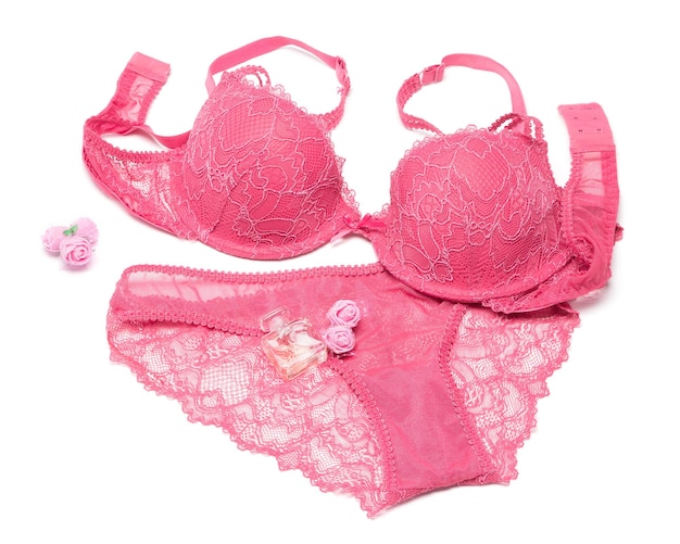 Conjunto de lencería sexy de sujetador y panty con perfume y pequeñas flores color de rosa sobre fondo blanco.