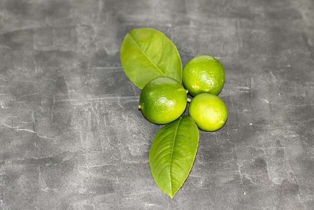 Conjunto de limones verdes frescos sobre fondo gris