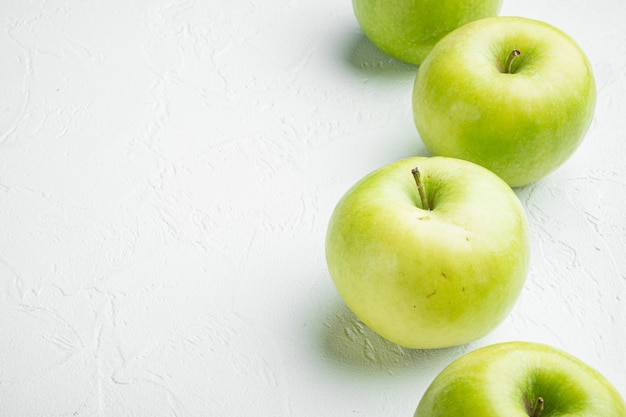 Conjunto de manzana verde, sobre fondo de mesa de piedra blanca, con espacio para copiar texto