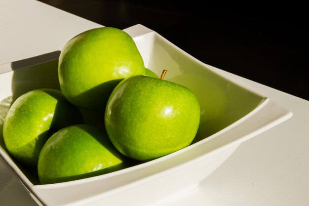 Un conjunto de manzanas verdes en un bol. De cerca. Manzanas verdes. Luz dura. Sombra.