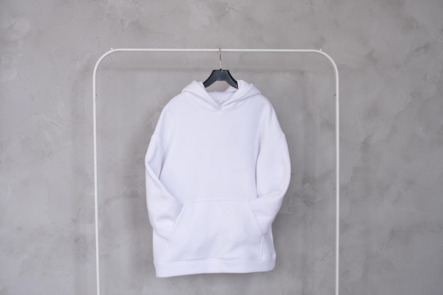 Un conjunto de maquetas de una sudadera blanca con una capucha y un bolsillo colgando de una percha