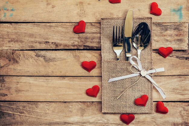 Conjunto de mesa para el Día de San Valentín de celebración. Configuración de lugar de mesa de madera y cubiertos con corazón rojo para el día de San Valentín.