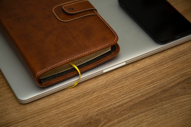 Conjunto de negocios, cuaderno de cuero, computadora portátil y teléfono inteligente en una mesa de madera