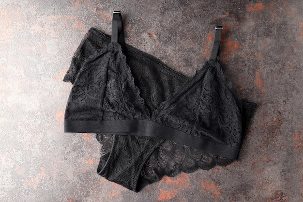 Conjunto negro de ropa interior femenina sobre fondo con textura