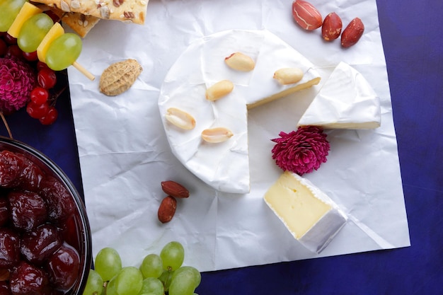 Conjunto o surtido de quesos closeup Diferentes tipos de quesos con nueces bayas frutas mermelada de cereza y miel sobre un fondo azul