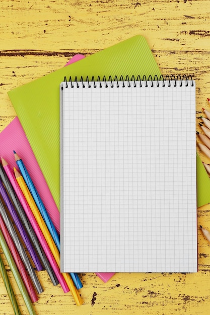 Conjunto de oficina con cuadernos y lápices sobre fondo de madera amarillo