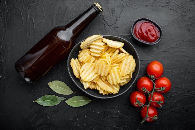 Conjunto de papas fritas, con botella de cerveza, en la mesa de piedra negra, vista superior plana