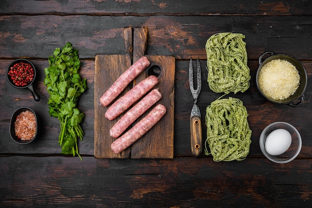 Conjunto de pastas y salchichas verdes frescas, sobre fondo de mesa de madera oscura antigua, vista superior plana