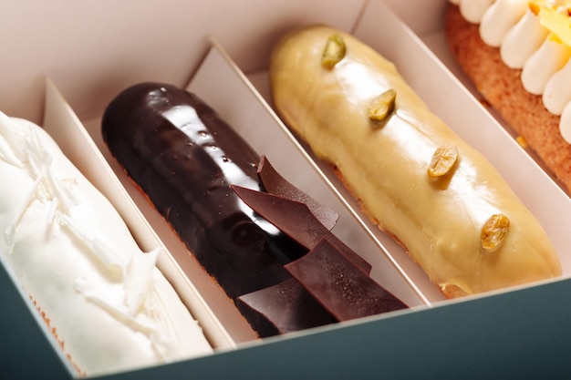 Conjunto de pasteles eclair con diferentes rellenos en un primer plano de caja Postre francés tradicional