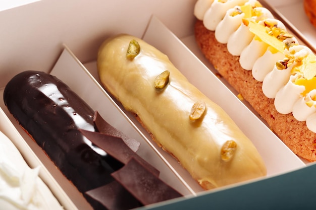 Conjunto de pasteles eclair con diferentes rellenos en un primer plano de caja Postre francés tradicional