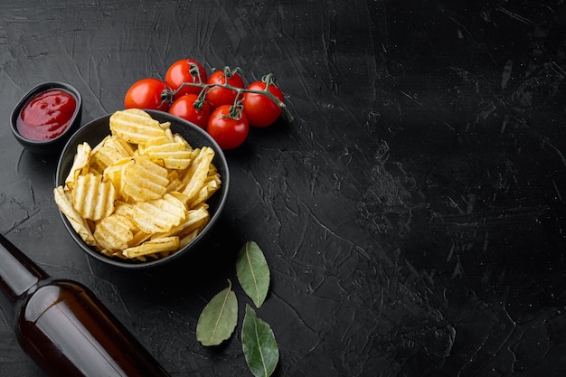 Conjunto de patatas fritas crujientes, con botella de cerveza, sobre piedra negra