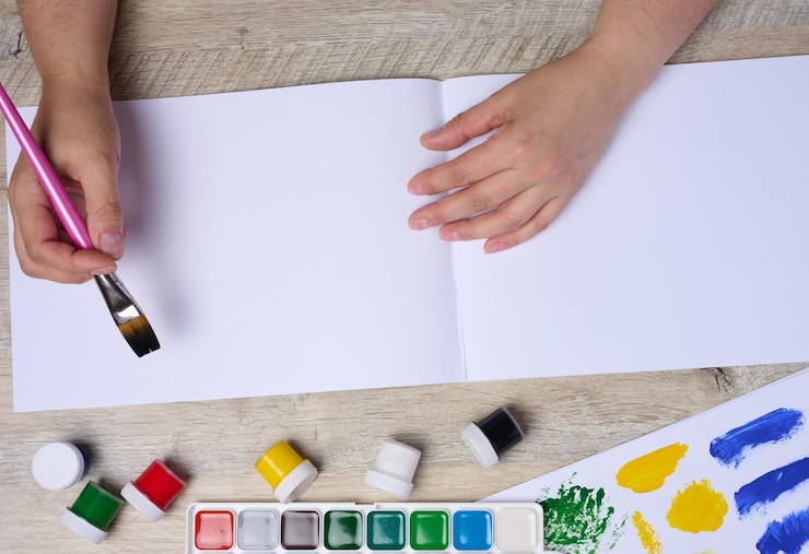 Foto conjunto de pinturas de acuarela, pinceles y papel con diferentes trazos y colores manos femeninas con un pincel