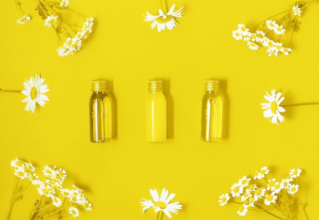 Un conjunto plano de botellas de maquillaje con productos cosméticos con flores de camomila en tono amarillo