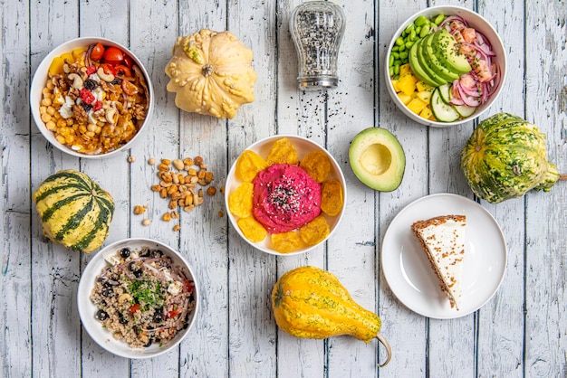 Conjunto de platos de comida saludable con aguacate, cebolla roja, quinua cocida, aceitunas españolas, frutos secos con bayas, calabaza y semillas de sésamo.