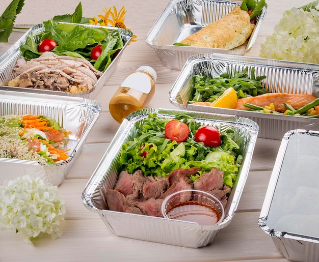 Conjunto de platos de dieta en recipientes sobre un fondo de madera clara Dieta para llevar y comida saludable