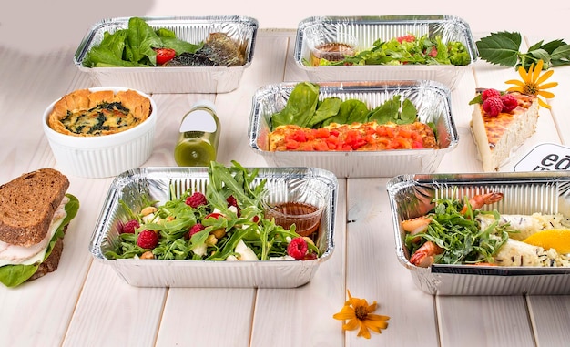 Conjunto de platos de dieta en recipientes sobre un fondo de madera clara Dieta para llevar y comida saludable