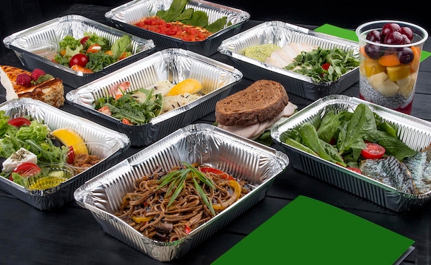 Un conjunto de platos dietéticos en recipientes sobre un fondo de madera oscura Dieta para llevar y comida saludable