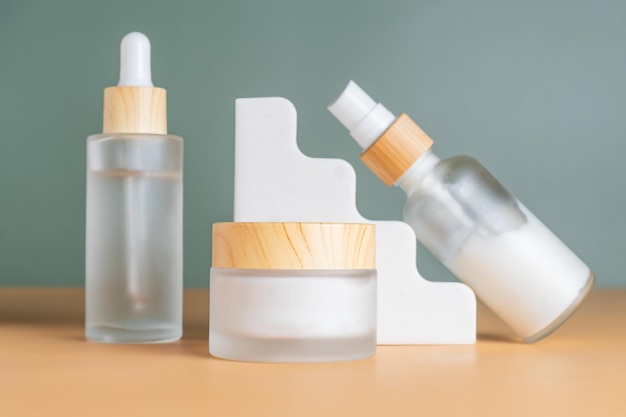 Conjunto de productos cosméticos en botellas de vidrio esmaltado en podios de coco de cemento Envases de maquillaje sin marca para el cuidado de la piel