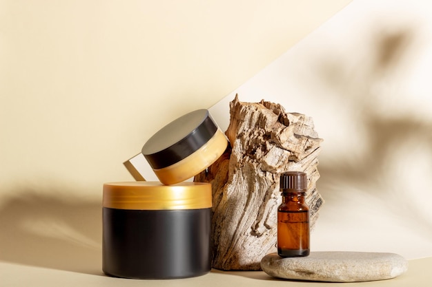 Un conjunto de productos cosméticos junto a un tronco y sombras duras sobre un fondo beige Cosmética orgánica natural