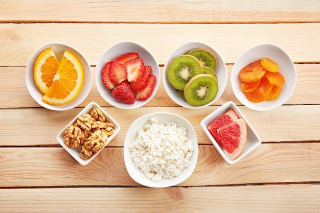 Foto conjunto de productos dietéticos en platillos sobre fondo de madera