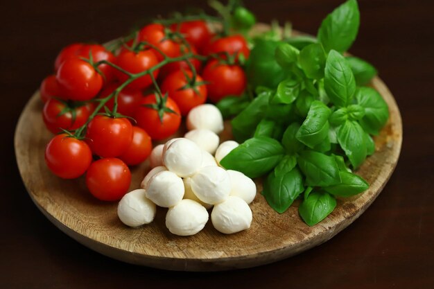 Un conjunto de productos para ensalada caprese Tomates, albahaca y mozzarella en una tabla de madera