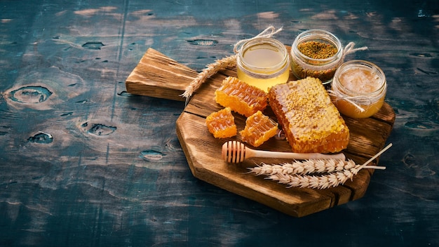 Un conjunto de productos de miel y abejas Miel en panal Sobre un fondo de madera negra Espacio libre para texto Vista superior