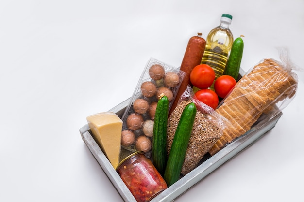 Un conjunto de productos sobre un fondo blanco. Comestibles, verduras, mantequilla, huevos y salchichas. Paquete de comida