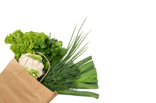 Un conjunto de productos verdes en una bolsa de papel. Aislado sobre fondo blanco. Compras en un supermercado o mercado.