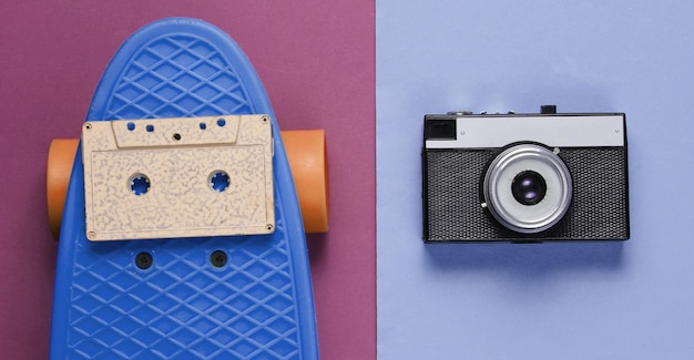 Foto conjunto retro con patineta azul con casete de audio y cámara retro sobre fondo de color. tiro del estudio. estilo de vida juvenil. vista superior