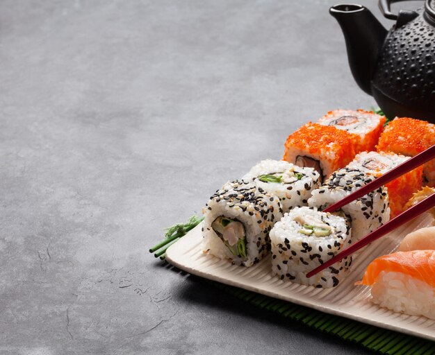 Conjunto de rollo de sushi y maki y té verde.