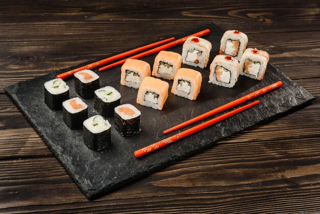 Conjunto de rollos japoneses en un plato de piedra con palillos.