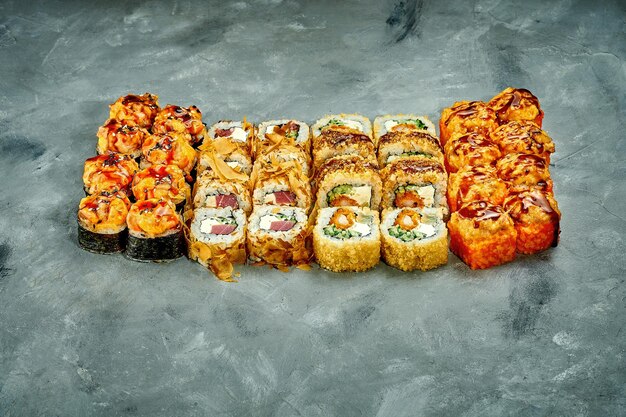 Conjunto de rollos de sushi con diferentes rellenos sobre un fondo gris Enfoque selectivo Grano de ruido agregar en la publicación