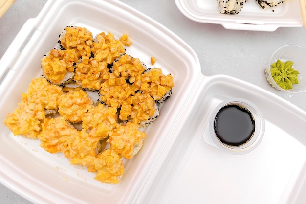 Foto conjunto de rollos de sushi de pescado con salmón y jengibre de sésamo wasabi empaquetado en una caja de plástico desechable de alimentos en fondo gris seafood food deliveryytake out service desde el concepto del restaurante