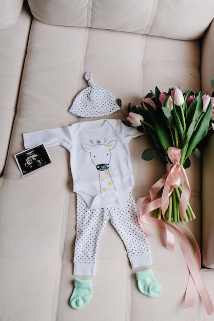 Conjunto de ropa de bebé en color blanco Accesorios para recién nacidos calcetines gorra ecografía o foto de niño Ramo de flores saludos para una fiesta en honor a embarazada en casa Vista superior trasera baby shower